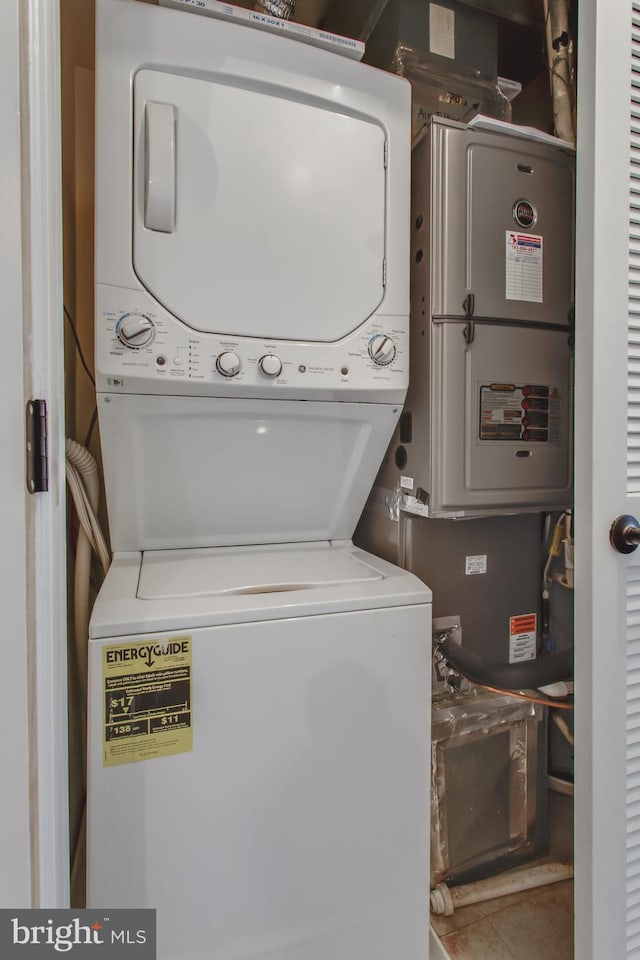 clothes washing area with tile patterned floors and stacked washer / drying machine