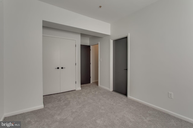 unfurnished bedroom with light carpet and a closet