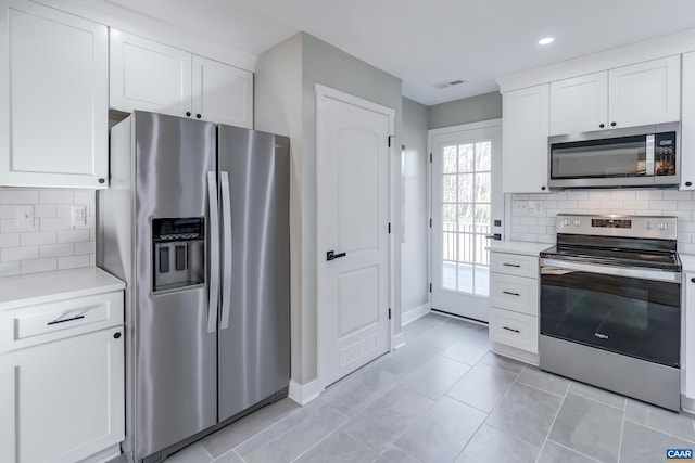 kitchen with white cabinetry, stainless steel appliances, light tile patterned floors, and tasteful backsplash