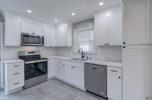 kitchen with white cabinets, sink, tasteful backsplash, light tile patterned floors, and appliances with stainless steel finishes