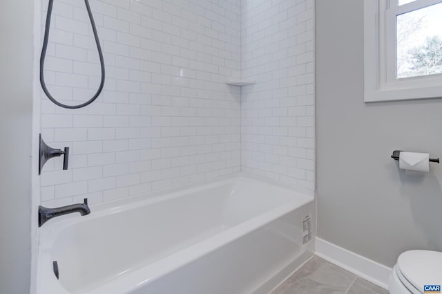 bathroom featuring tiled shower / bath, tile patterned floors, and toilet