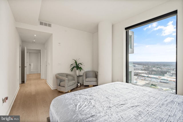 bedroom with access to exterior, light wood-type flooring, and multiple windows