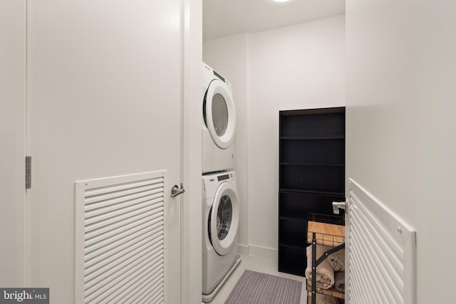 laundry area featuring light tile patterned floors and stacked washing maching and dryer