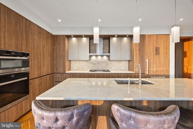 kitchen featuring white cabinetry, sink, hanging light fixtures, stainless steel gas cooktop, and light stone counters