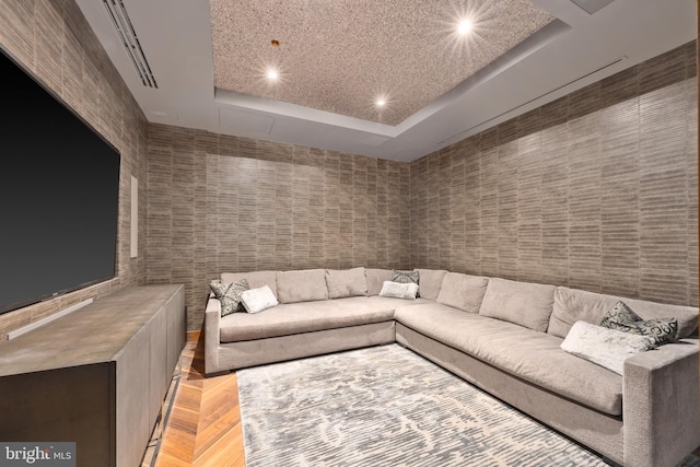 unfurnished living room featuring a raised ceiling, a textured ceiling, and light parquet flooring