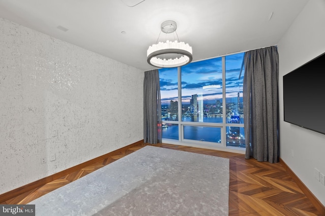 empty room with dark parquet flooring and an inviting chandelier