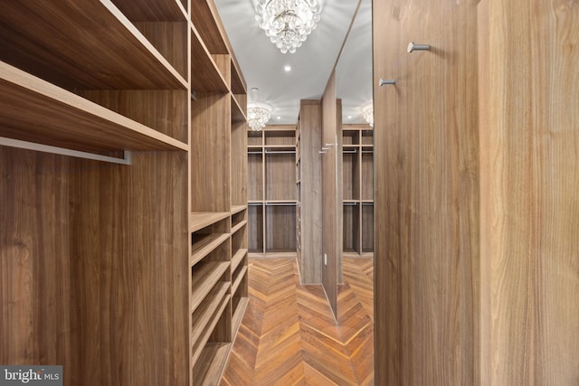 spacious closet featuring parquet flooring and an inviting chandelier