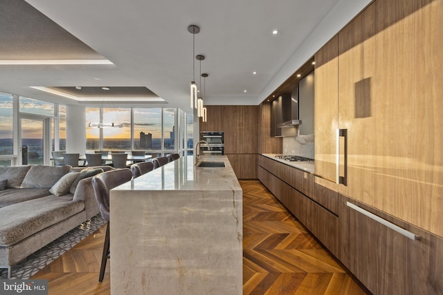 kitchen with a kitchen bar, dark parquet floors, a tray ceiling, pendant lighting, and a large island