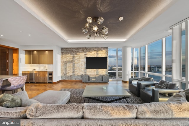 living room with parquet flooring, a raised ceiling, a wall of windows, a notable chandelier, and wine cooler