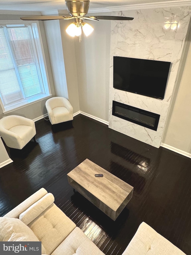 living room with a premium fireplace, wood-type flooring, ceiling fan, and crown molding