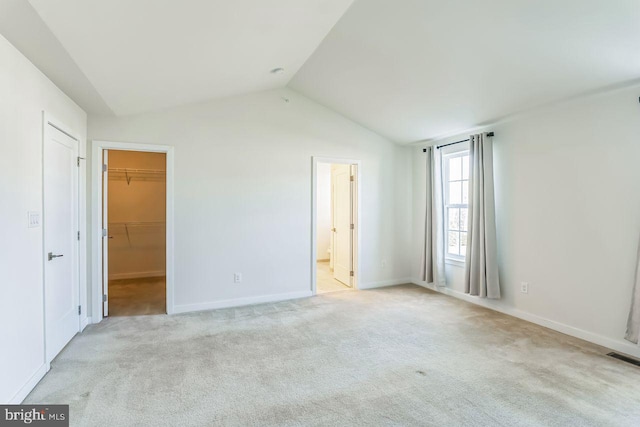 carpeted empty room featuring vaulted ceiling