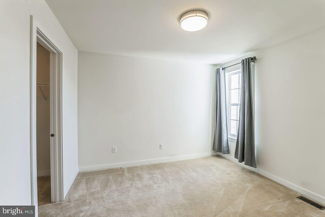 unfurnished bedroom featuring light carpet, a closet, and a spacious closet