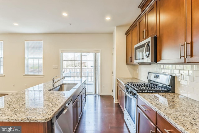 kitchen featuring light stone countertops, dark wood-type flooring, an island with sink, and stainless steel appliances