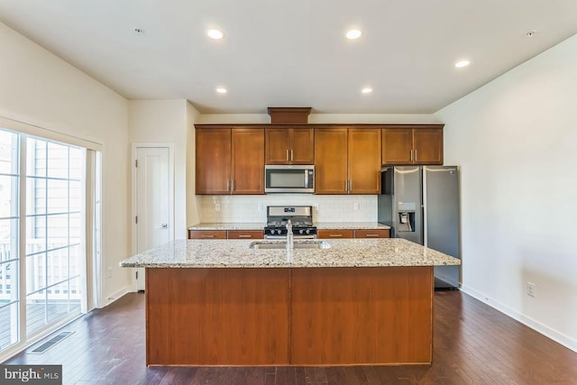 kitchen with a center island with sink, stainless steel appliances, dark hardwood / wood-style floors, and sink