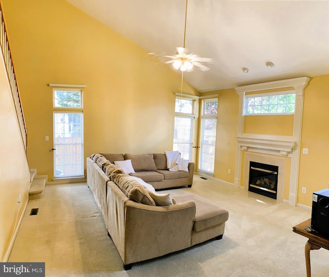 carpeted living room with ceiling fan, plenty of natural light, and high vaulted ceiling