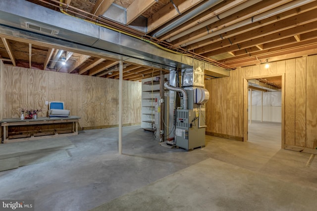 basement with heating unit and wood walls