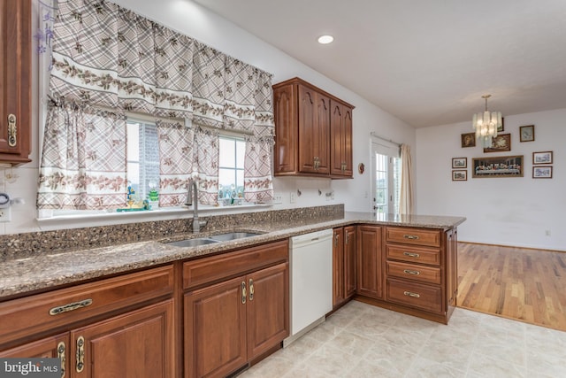 kitchen with sink, white dishwasher, a chandelier, pendant lighting, and stone countertops