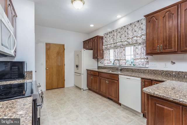 kitchen featuring tasteful backsplash, stone counters, sink, and white appliances