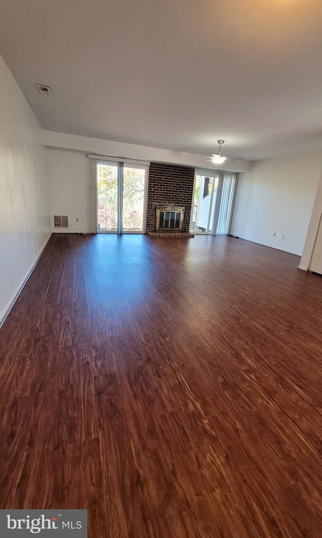 unfurnished living room featuring a fireplace, dark hardwood / wood-style flooring, and ceiling fan