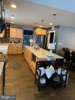 kitchen with dark hardwood / wood-style floors, light brown cabinets, stainless steel range oven, and hanging light fixtures