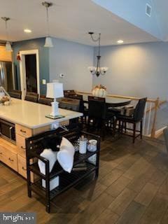 kitchen with pendant lighting, light brown cabinetry, an inviting chandelier, and dark wood-type flooring