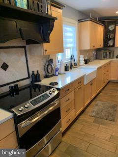 kitchen with stainless steel electric stove, light brown cabinets, light hardwood / wood-style floors, and extractor fan