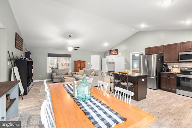 dining space with ceiling fan, lofted ceiling, and light hardwood / wood-style flooring