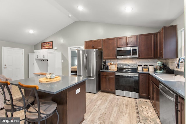 kitchen with sink, a center island, light hardwood / wood-style flooring, decorative backsplash, and appliances with stainless steel finishes