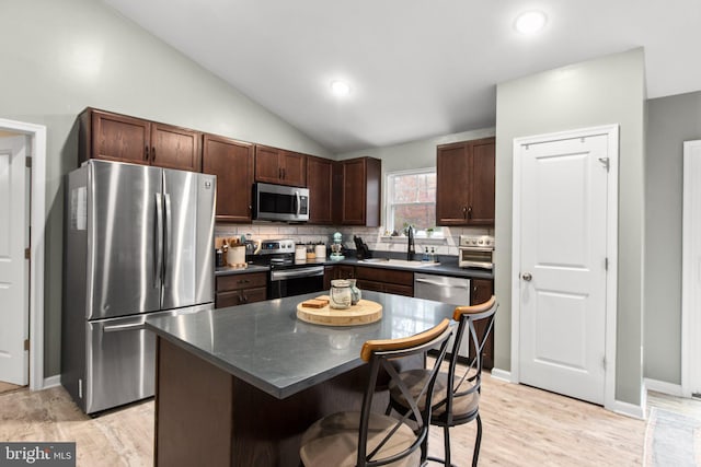 kitchen featuring light hardwood / wood-style flooring, a kitchen island, stainless steel appliances, and vaulted ceiling