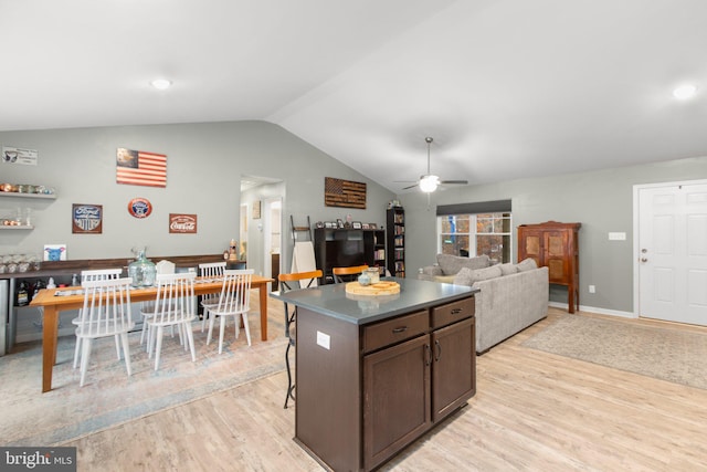 kitchen featuring light wood-type flooring, vaulted ceiling, dark brown cabinetry, and a kitchen island