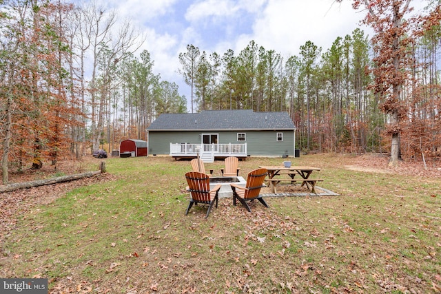 rear view of house with a lawn, a storage shed, an outdoor fire pit, and a wooden deck