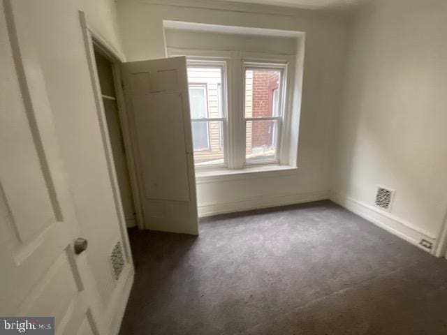 unfurnished bedroom with dark colored carpet