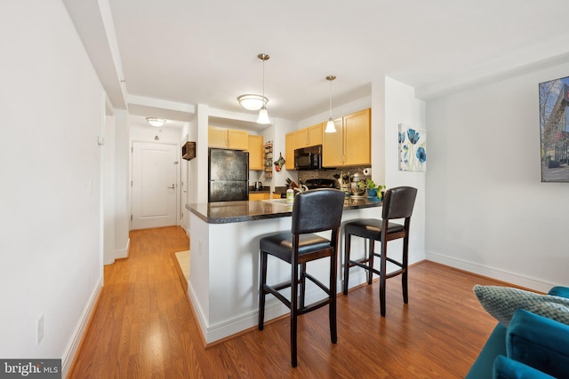 800 4th St SW Unit S312, Washington, DC 20024 - kitchen with black appliances, light brown cabinets, a peninsula, dark countertops, and light wood finished floors
