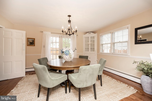 dining room featuring hardwood / wood-style flooring, a baseboard radiator, and a notable chandelier