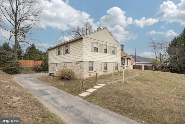 view of side of home with central AC unit and a lawn