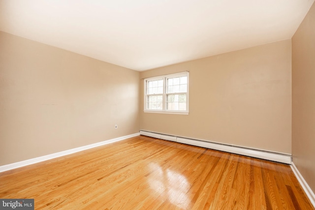 empty room with baseboard heating and hardwood / wood-style floors