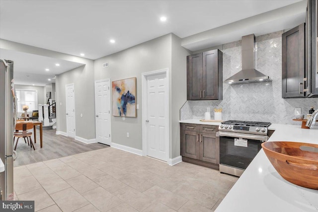 kitchen featuring gas stove, tasteful backsplash, dark brown cabinetry, and wall chimney range hood