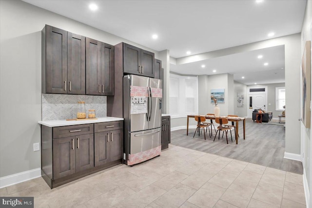 kitchen featuring decorative backsplash, stainless steel fridge, light hardwood / wood-style flooring, and dark brown cabinets