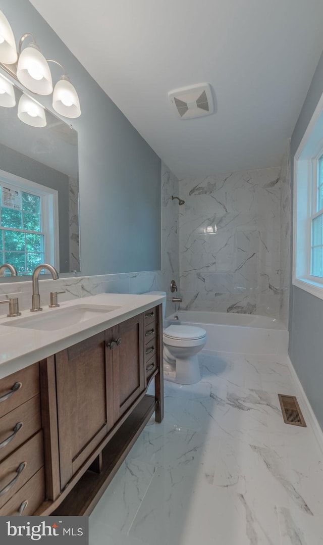 full bathroom featuring vanity, tiled shower / bath combo, and toilet