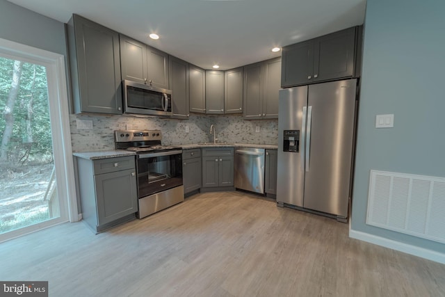 kitchen with light hardwood / wood-style flooring, gray cabinetry, sink, and stainless steel appliances