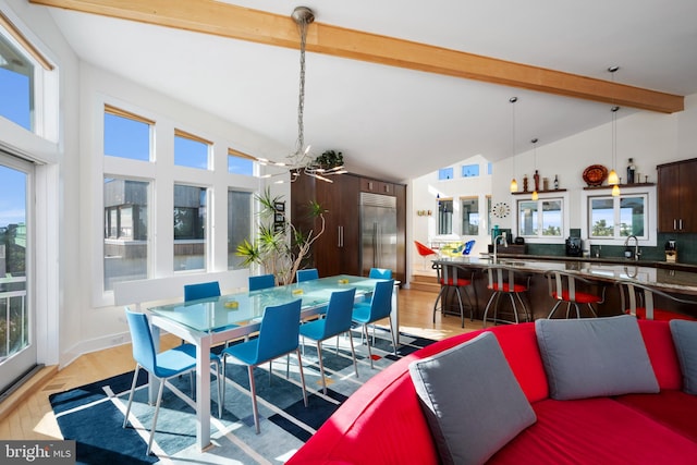 dining room with beam ceiling, a wealth of natural light, light hardwood / wood-style flooring, and high vaulted ceiling