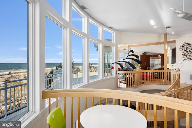 interior space with a healthy amount of sunlight, a water view, and a beach view