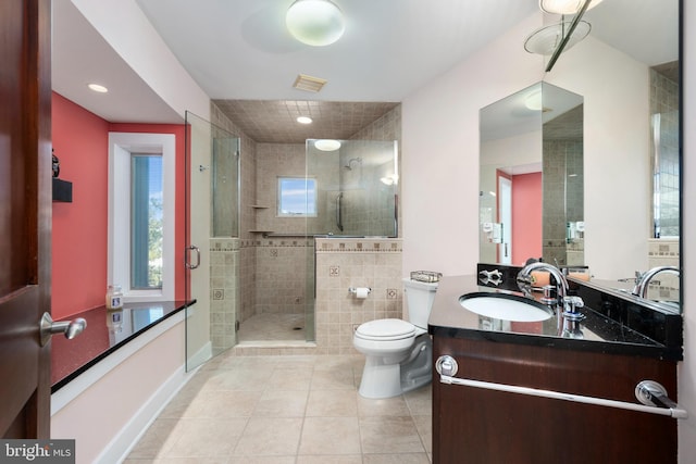 bathroom featuring vanity, tile patterned flooring, toilet, tile walls, and an enclosed shower