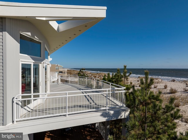 balcony with a water view and a view of the beach