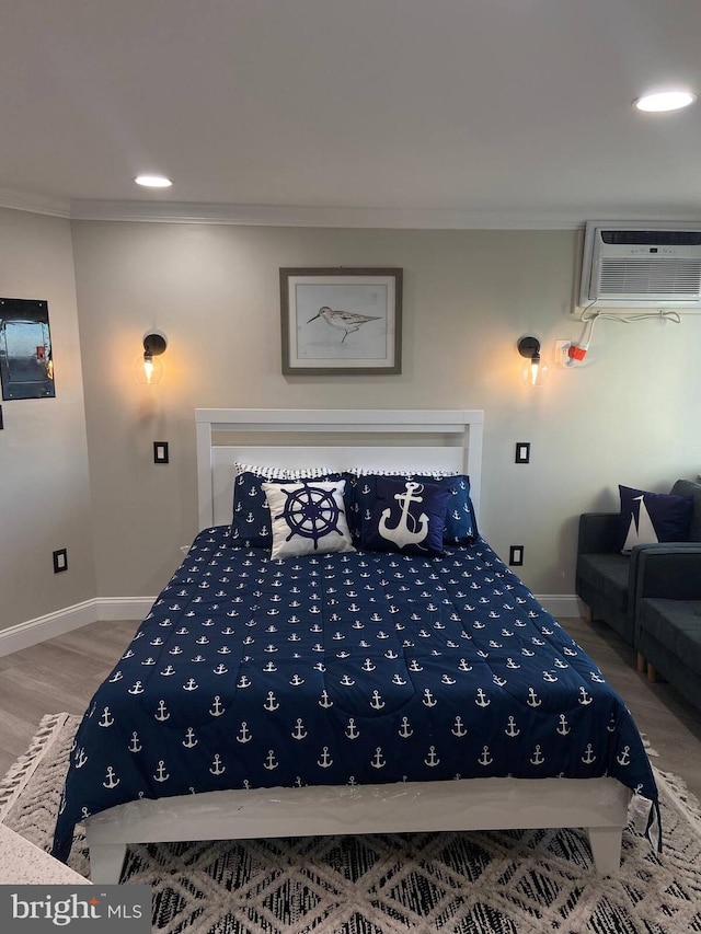 bedroom featuring a wall mounted AC, ornamental molding, and hardwood / wood-style flooring