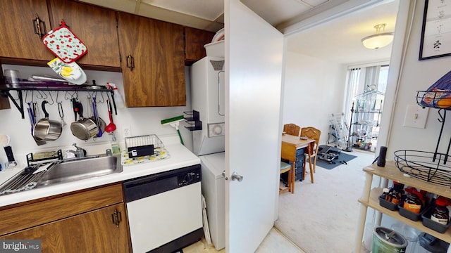 kitchen featuring light carpet, sink, dishwasher, and stacked washer / drying machine