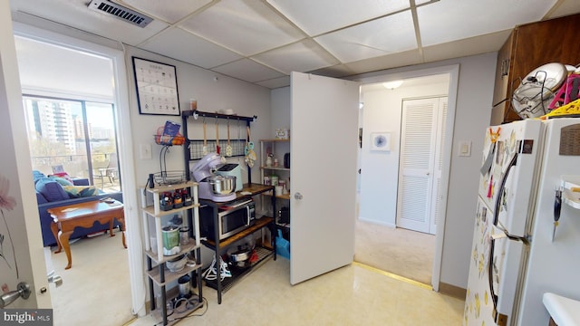 interior space featuring a paneled ceiling and white fridge