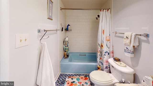 bathroom featuring tile patterned floors, toilet, and shower / bath combo with shower curtain