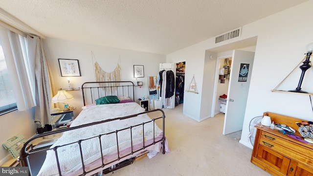 bedroom featuring light carpet, a closet, a spacious closet, and a textured ceiling