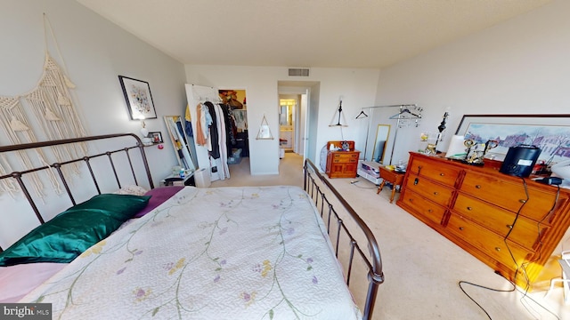 bedroom with a walk in closet, a closet, and light colored carpet